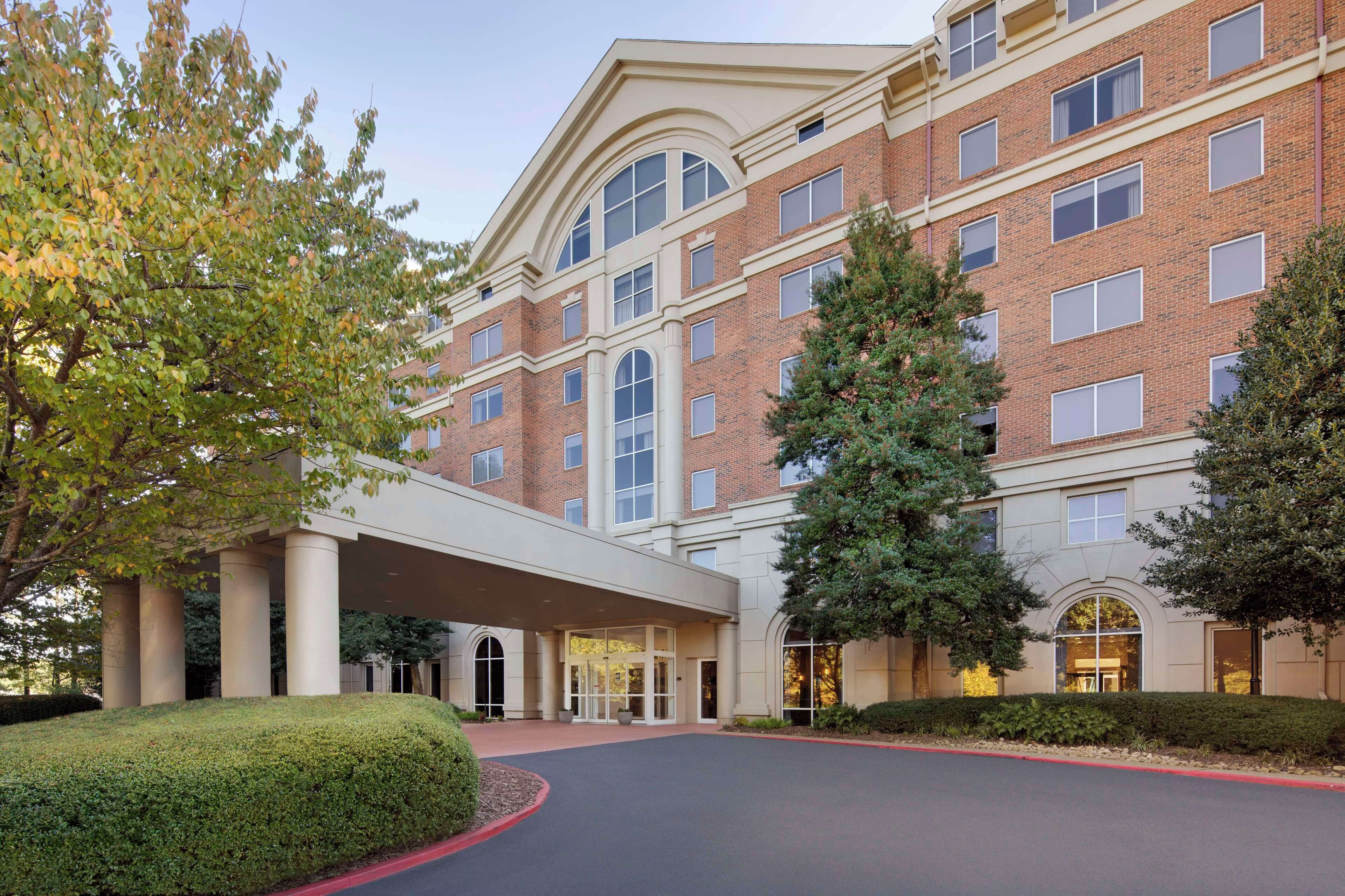 A multi-story hotel with a brick facade, large windows, and a covered entrance.