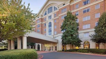 A multi-story hotel with a brick facade, large windows, and a covered entrance.