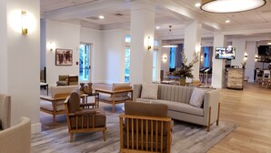 A spacious living area with a sofa, chairs, and a television. - DoubleTree by Hilton Atlanta - Roswell (Roswell)