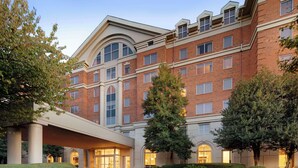 A multi-story hotel with a brick facade, large windows, and a covered entrance area. - DoubleTree by Hilton Atlanta - Roswell (Roswell)