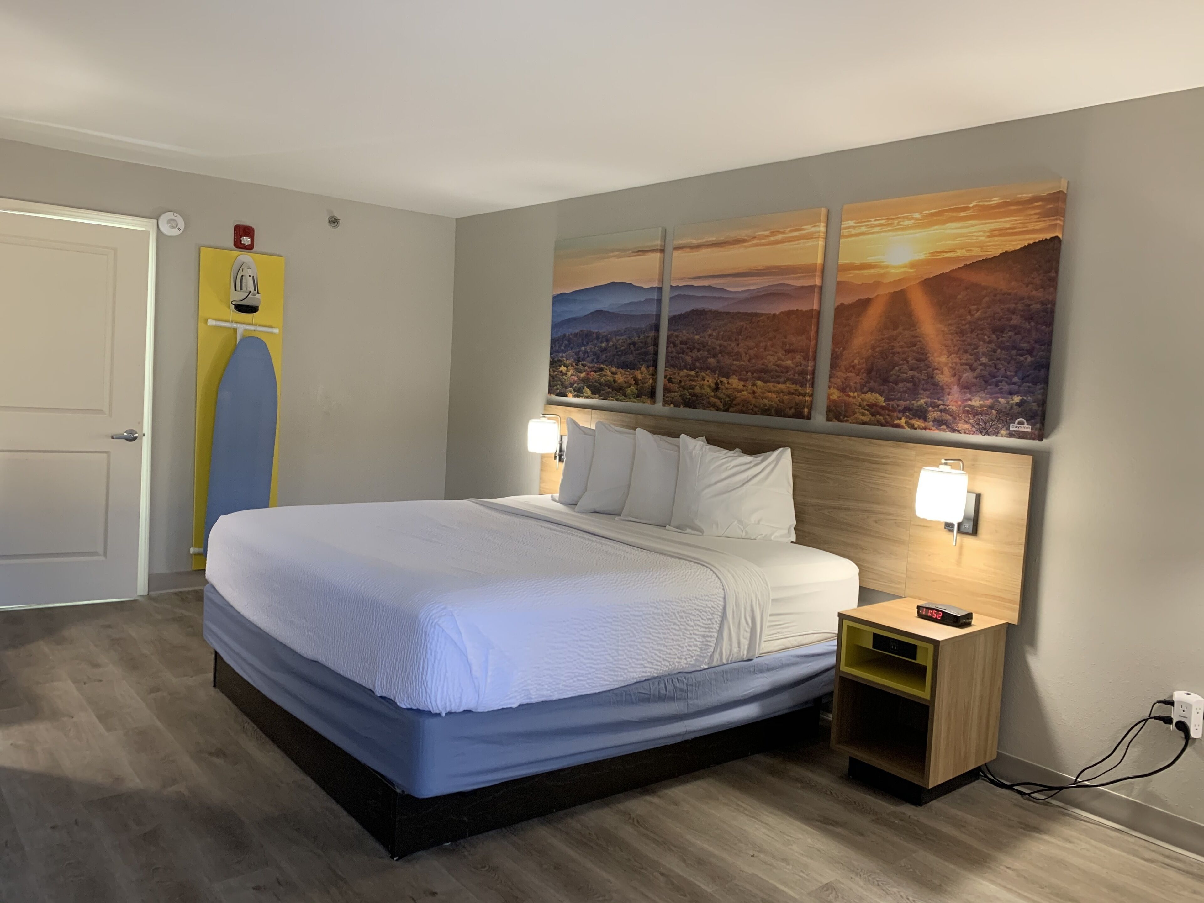A neatly made bed with white linens, a wooden headboard, and two bedside lamps.