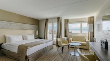 Habitación de hotel con cama, sofá, una mesita, televisión y vistas a la ciudad.