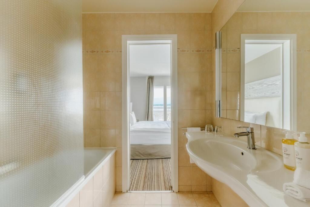 Un baño de hotel con una bañera grande, un lavamanos y un espejo.