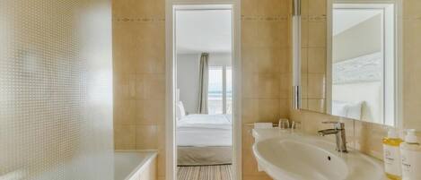 Un baño de hotel con una bañera grande, un lavamanos y un espejo.