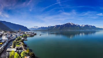 Une ville côtière avec un lac paisible, des montagnes en arrière-plan et un bâtiment moderne doté de balcons sur la droite.