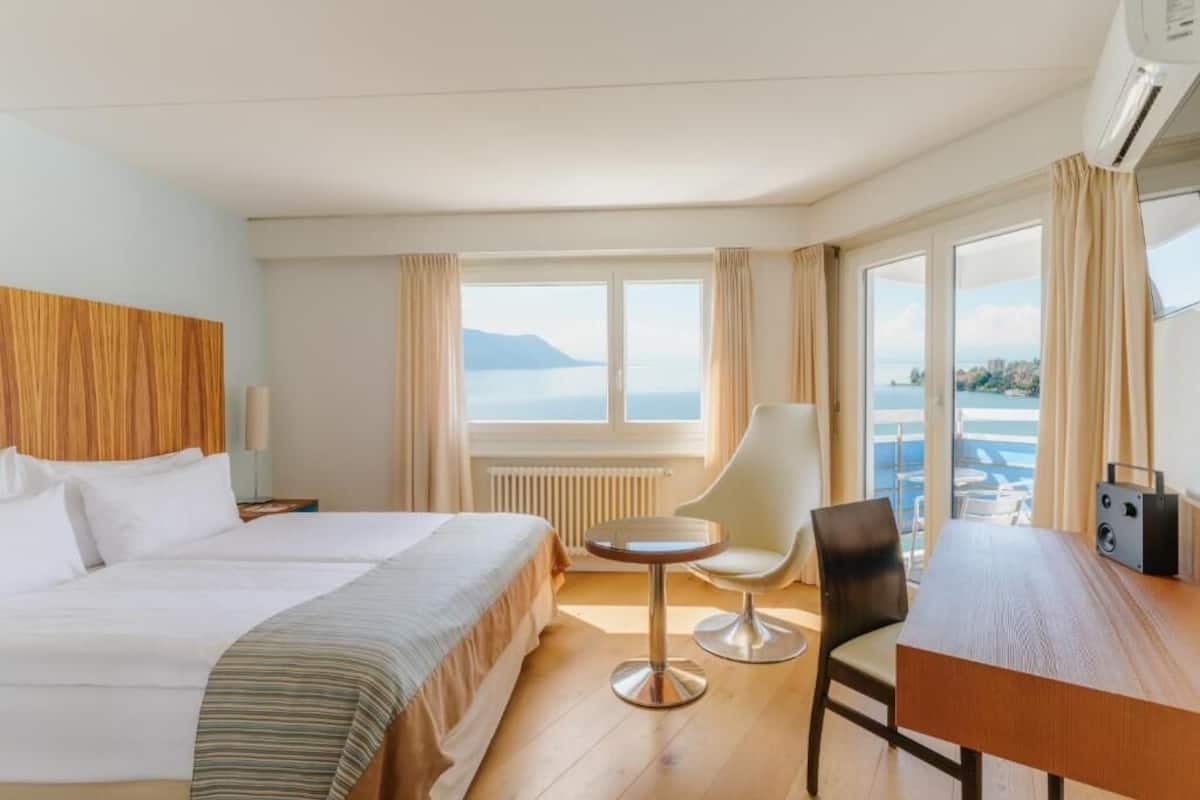 Habitación de hotel con cama, una mesa redonda, una silla y vista al mar.