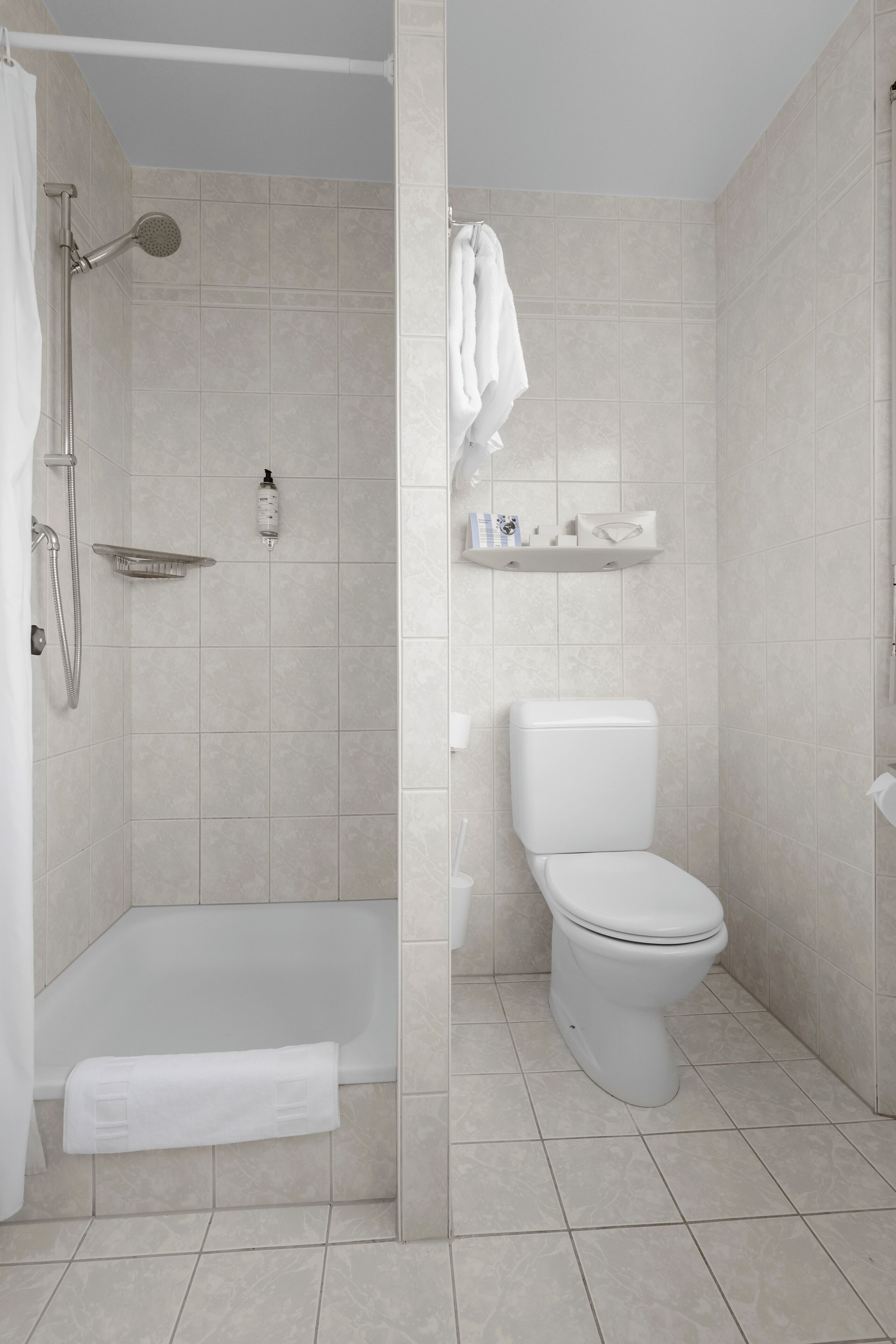 Un baño con ducha, inodoro y toallero.