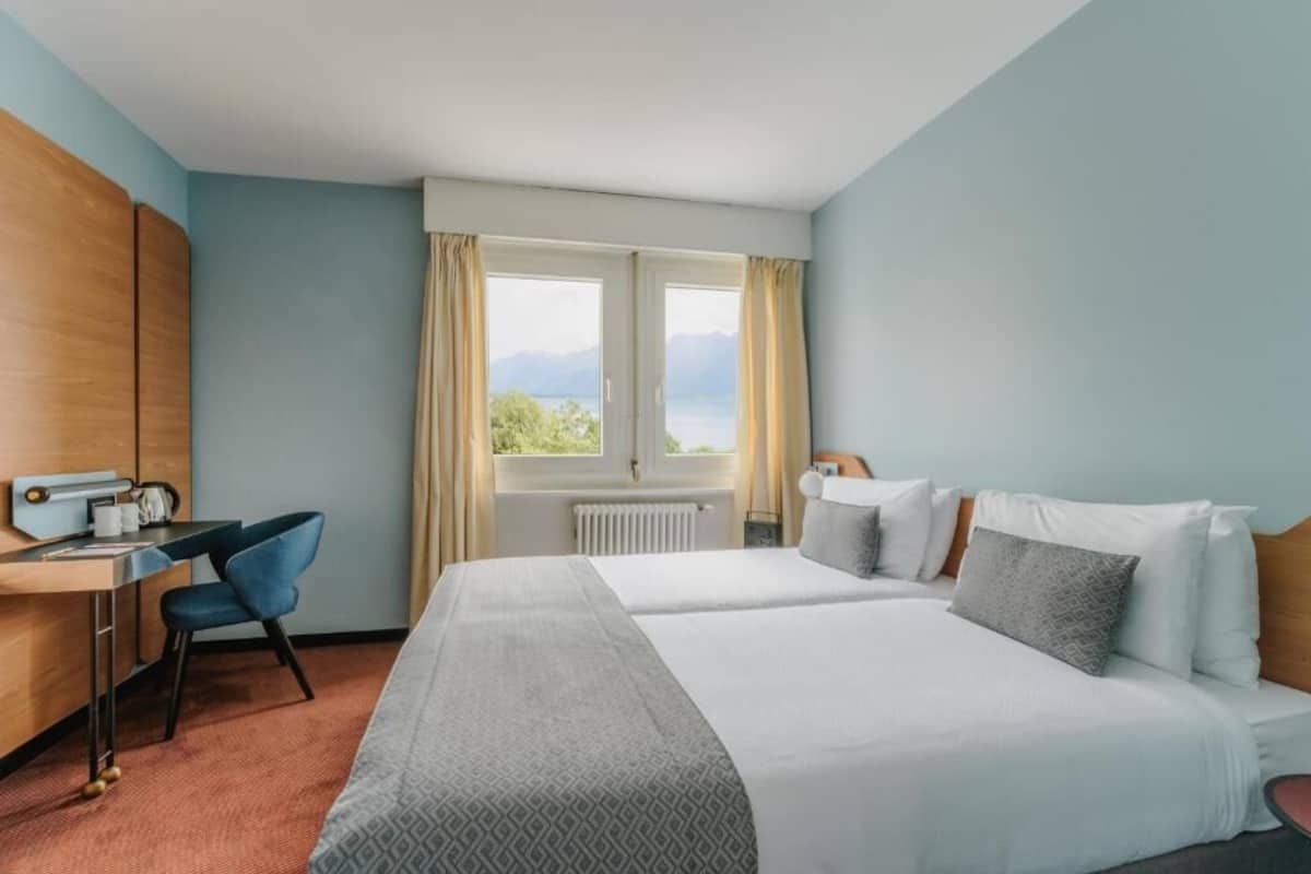 Una habitación de hotel con una cama, un escritorio, una silla y una ventana con vistas.
