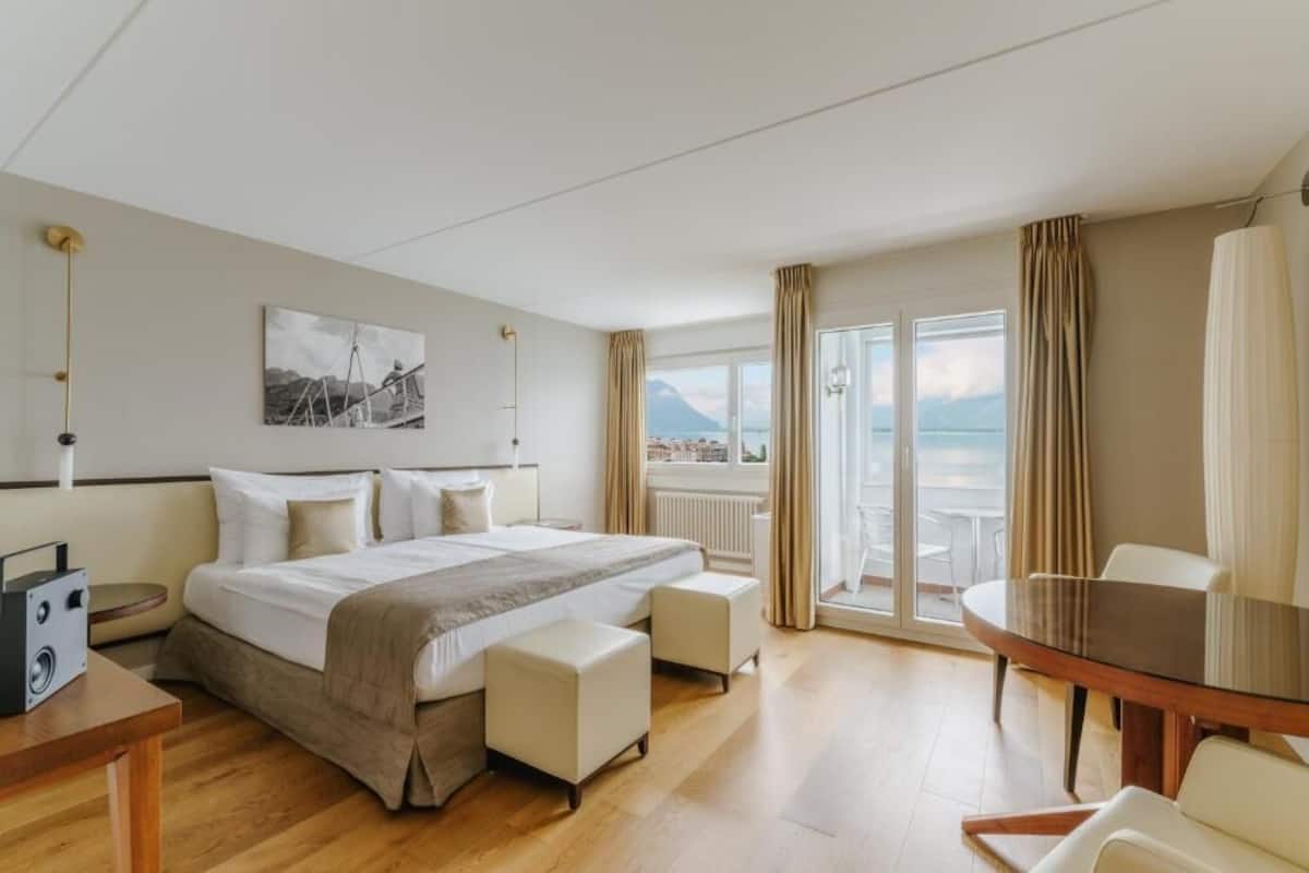 Habitación de hotel con cama, una mesa, una silla, un escritorio, una lámpara, un cuadro en la pared y vistas al mar.