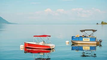 Deux bateaux sont amarrés à un quai sur un lac paisible, avec une montagne en arrière-plan.