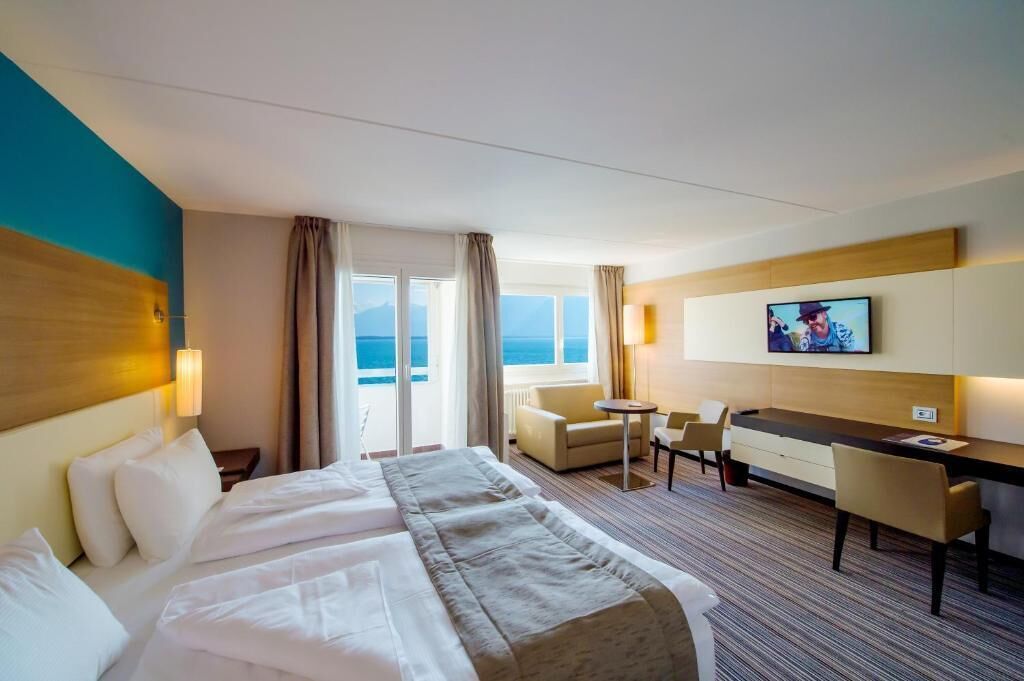 Habitació d'hotel amb un llit, escriptori, cadira, televisió i vista al mar.