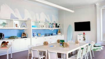 Children can play, learn, and dine at this well-organized playroom with a long table and comfortable chairs.