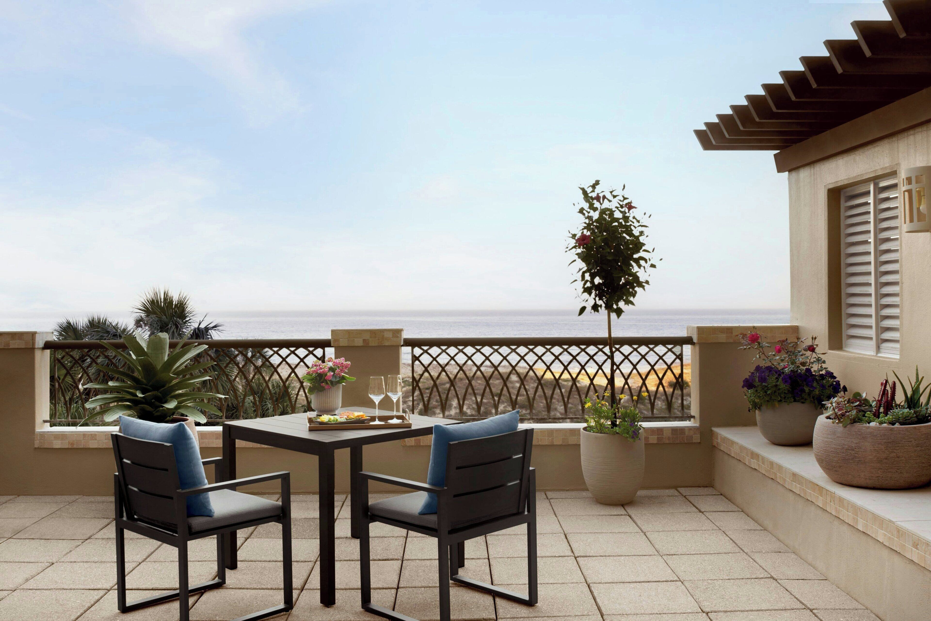 Une terrasse avec deux chaises, une table et des plantes en pot.