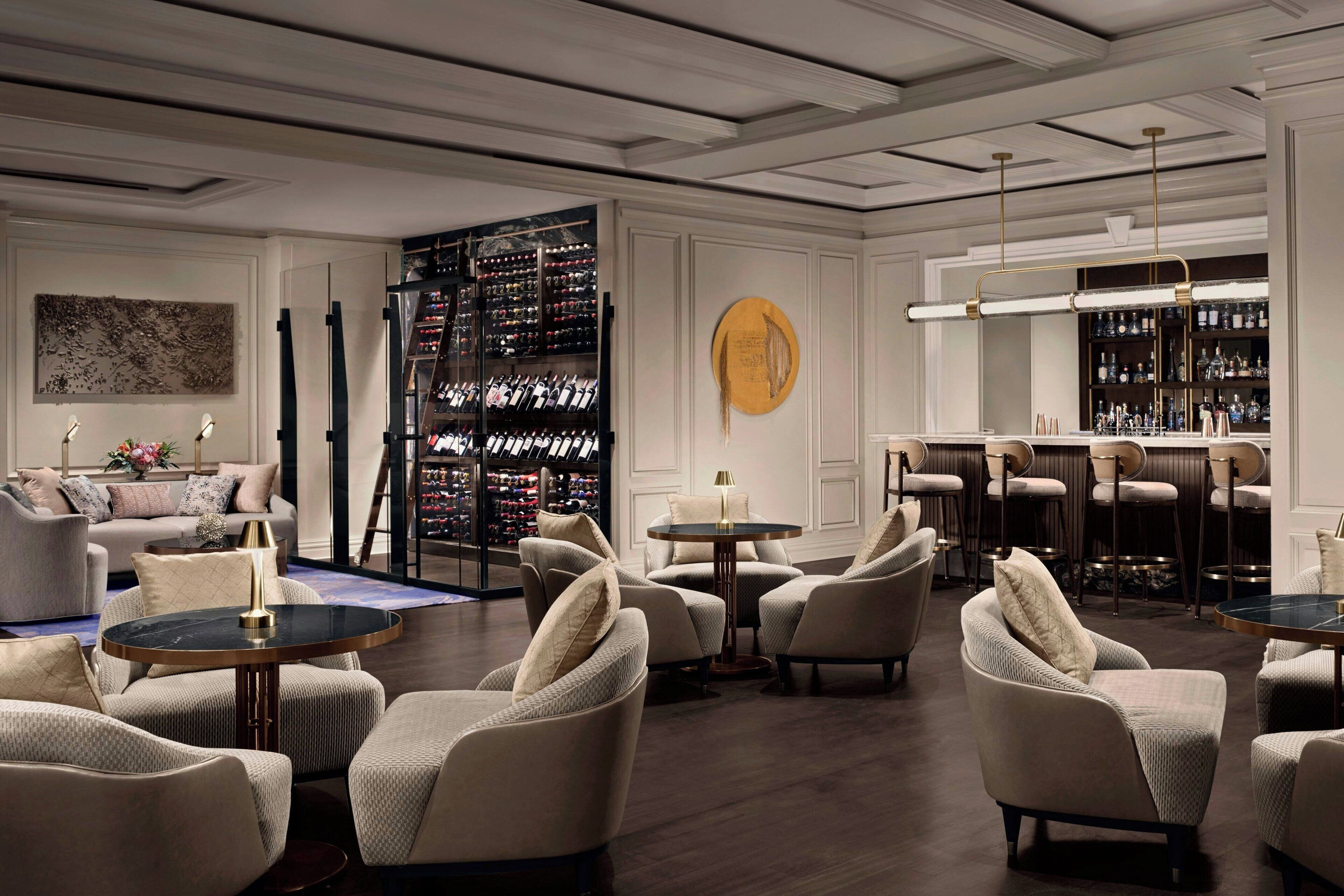 Ein moderner Lounge-Bereich mit Sofas, Sesseln und einer Bar mit Weinkühler.