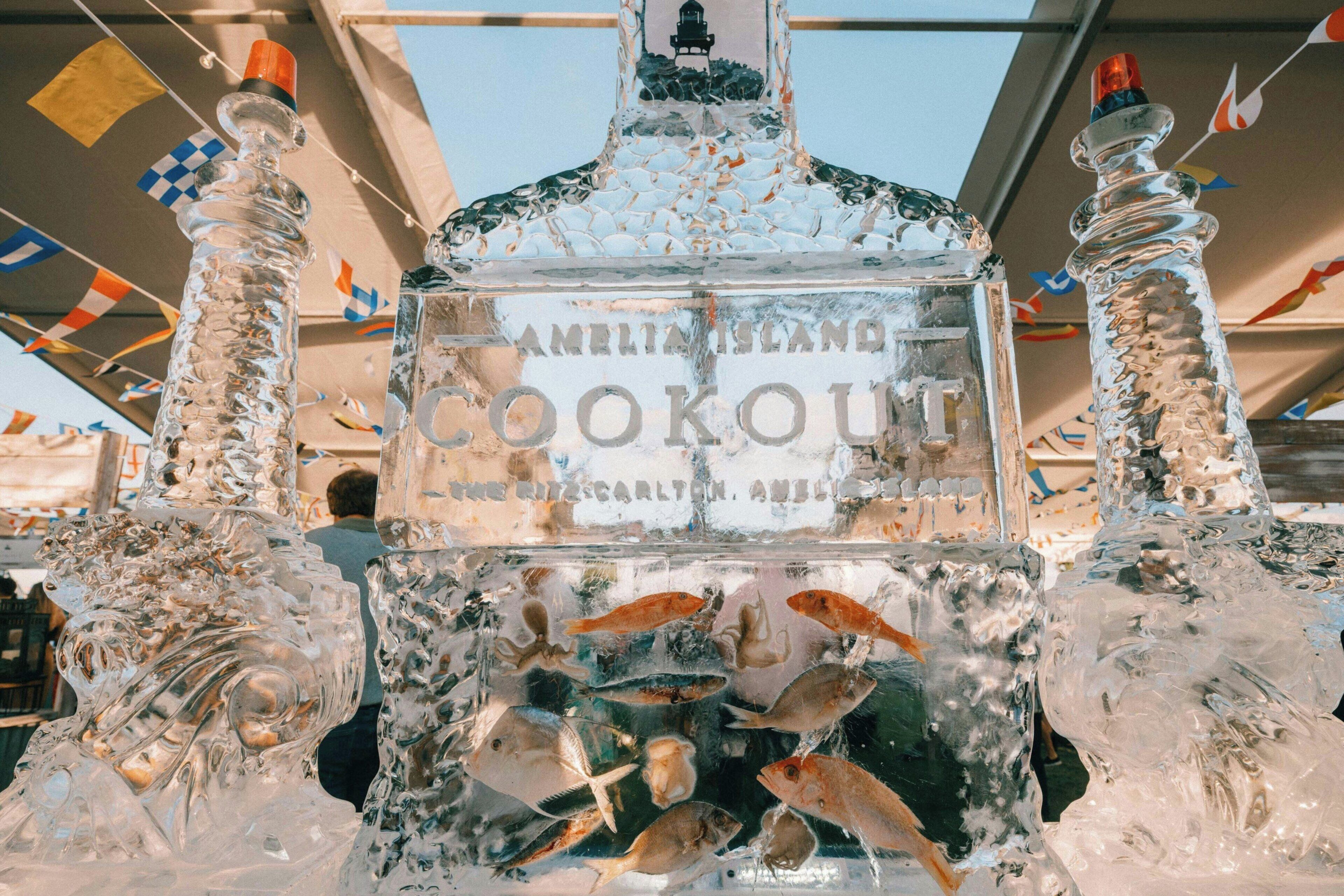 A large ice sculpture of a bottle with fish inside, surrounded by flags.