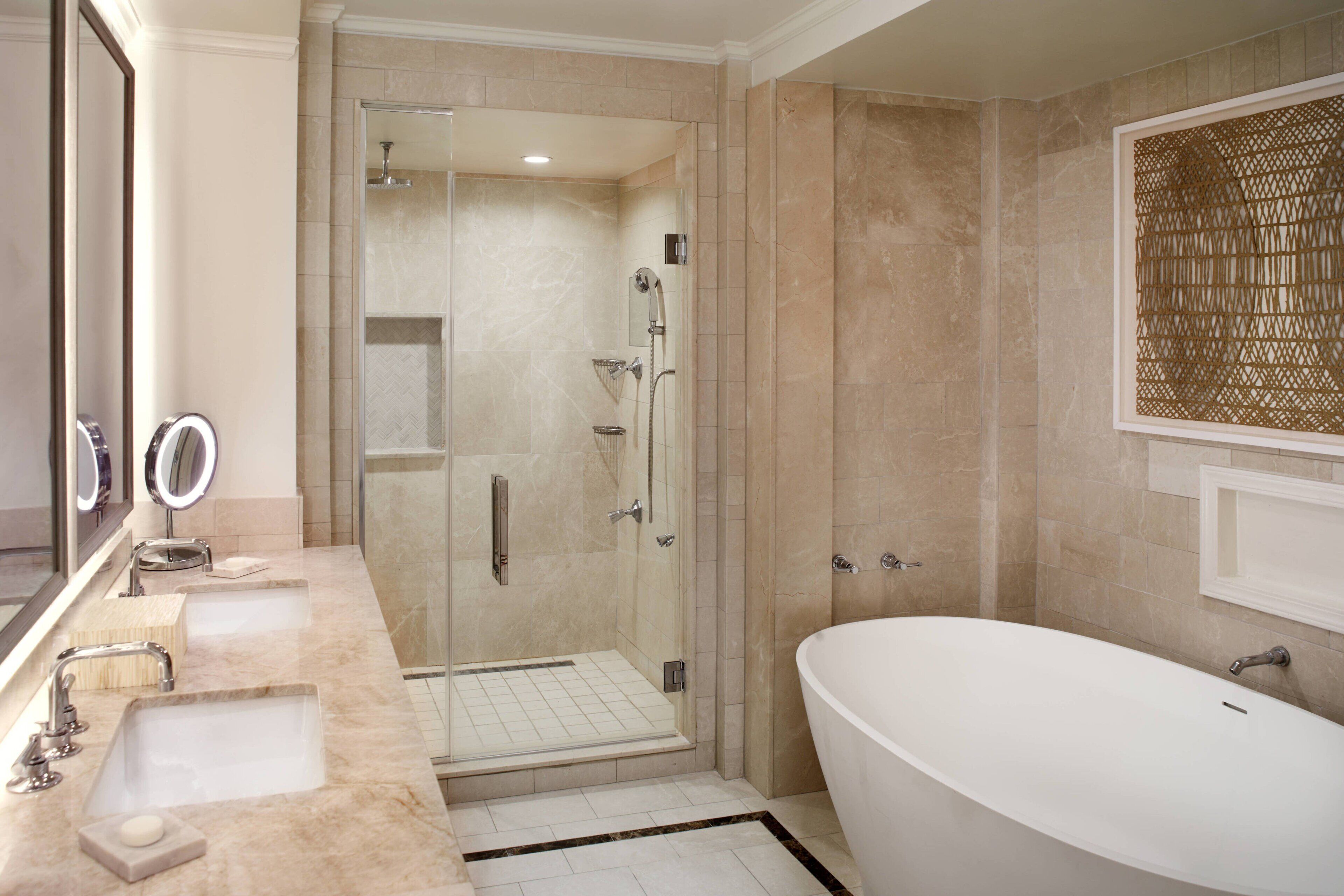 Ein modernes Badezimmer mit einer gläsernen Duschkabine, einer freistehenden Badewanne und einem Waschtisch mit zwei Waschbecken.
