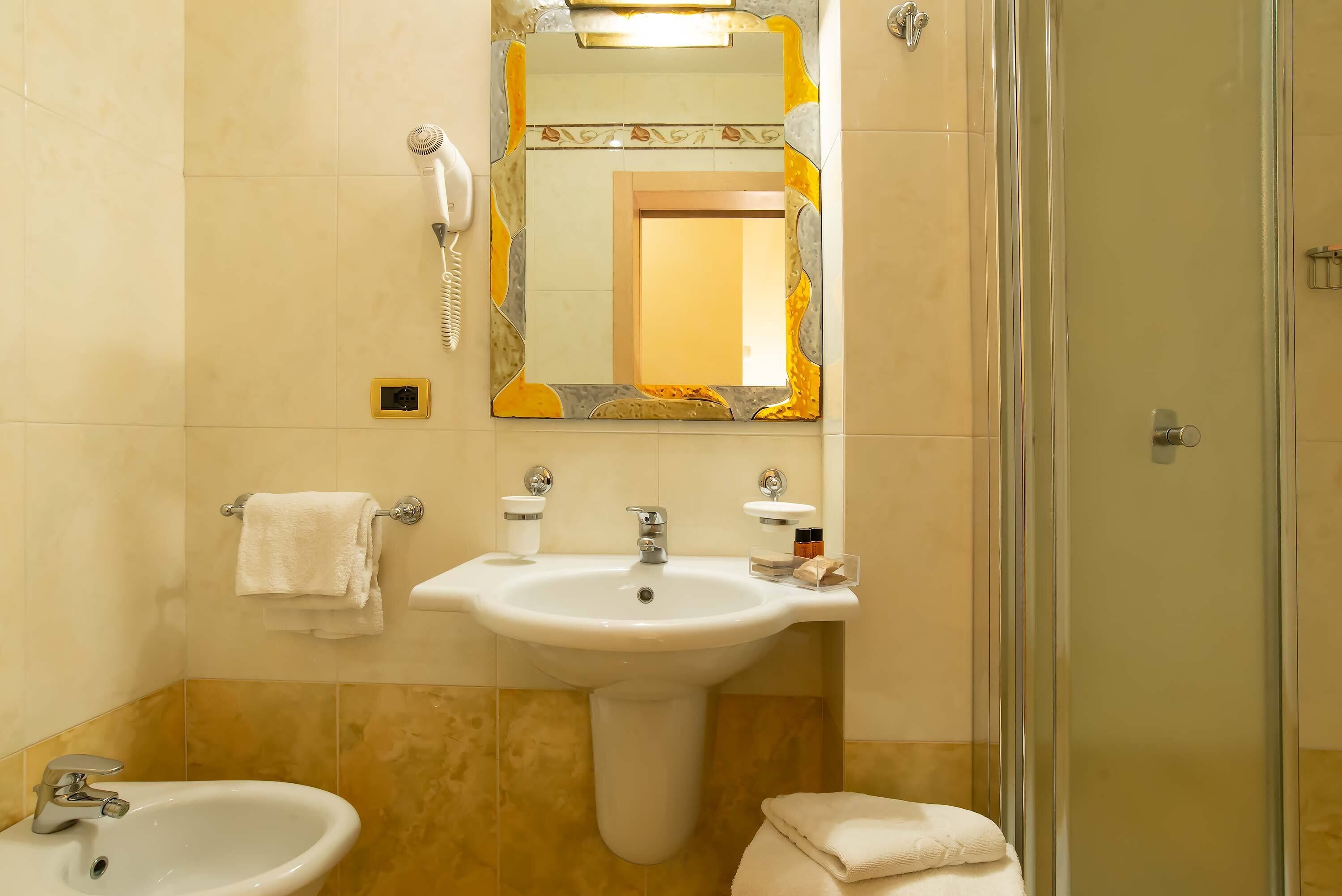 Un baño con lavamanos, espejo y ducha.