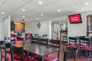 Une salle de conférence équipée d’une grande table, de plusieurs chaises, d’une horloge et d’un écran de télévision diffusant une publicité pour un accès Wi-Fi gratuit.