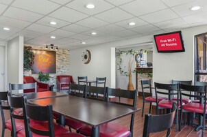 Un salón de conferencias con una gran mesa, varias sillas, un reloj y una pantalla de televisión que anuncia Wi-Fi gratuito.