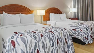 Habitación de hotel con dos camas, cabeceros de madera, ropa de cama blanca y un ventanal con cortinas.
