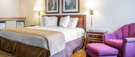 A hotel room with a bed, a nightstand, a chair, and two wall-mounted lamps.