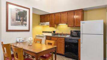 A compact kitchen with wooden cabinets, a white refrigerator, a stove, and a microwave.