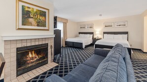 Una habitación de hotel con chimenea, dos camas, un sofá y un cuadro en la pared.