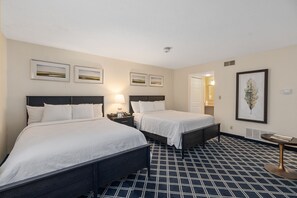 A hotel room with two beds, a small table, and a wall-mounted artwork.
