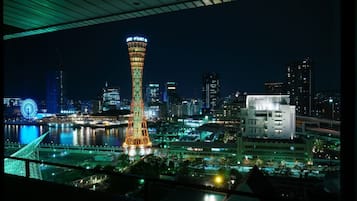 Une vue nocturne d’une ville, avec une tour imposante portant l’inscription « THE PORT OF » et une grande roue.