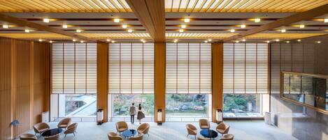 A spacious conference room with a high ceiling, large windows, and a view of the outdoors.
