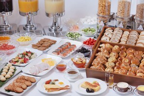 Un bufé con diversas opciones de comida, como frutas, verduras, carnes y pastelería.