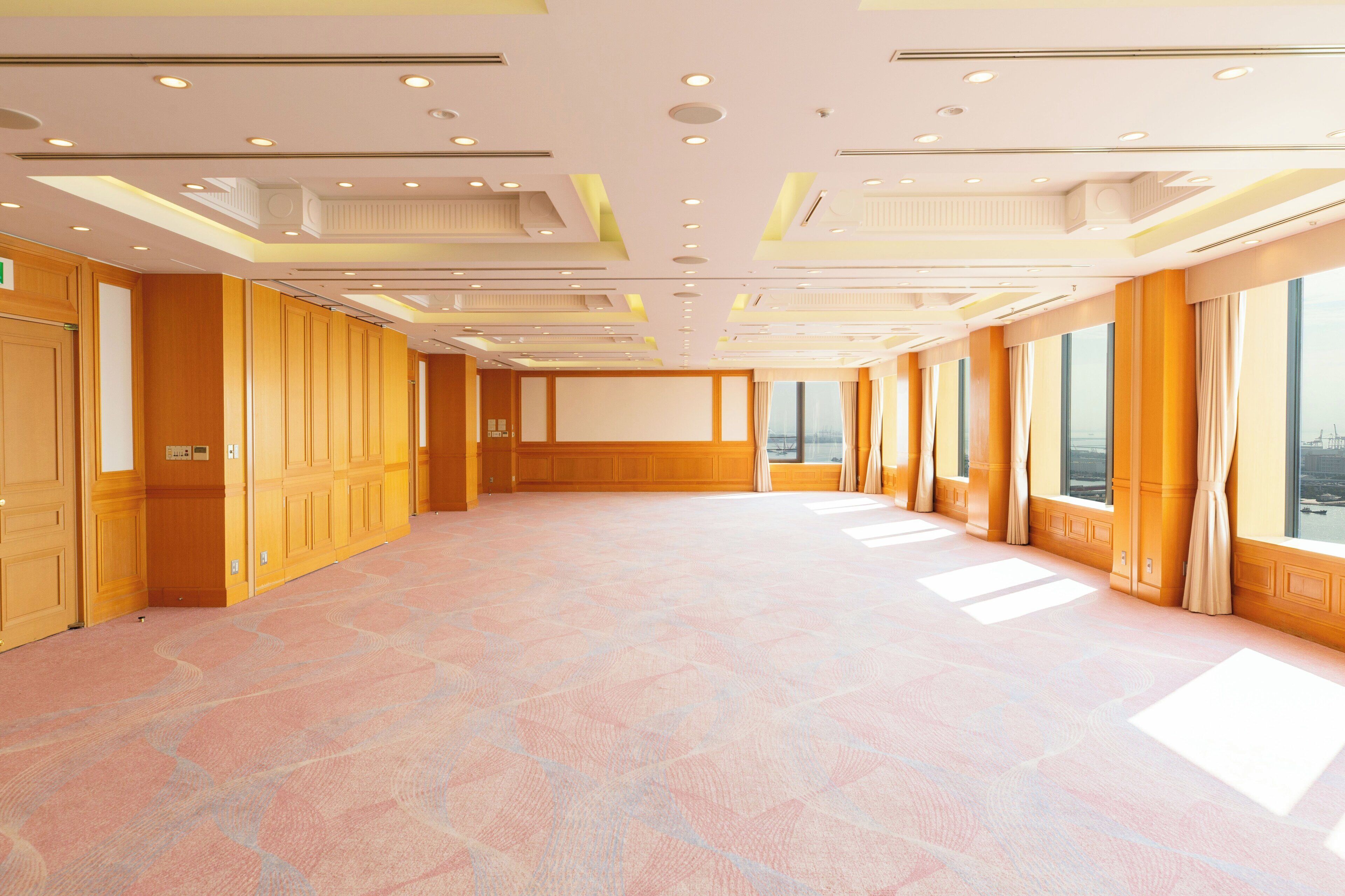 A spacious conference room with a patterned carpet, wooden paneling, and large windows offering a view.