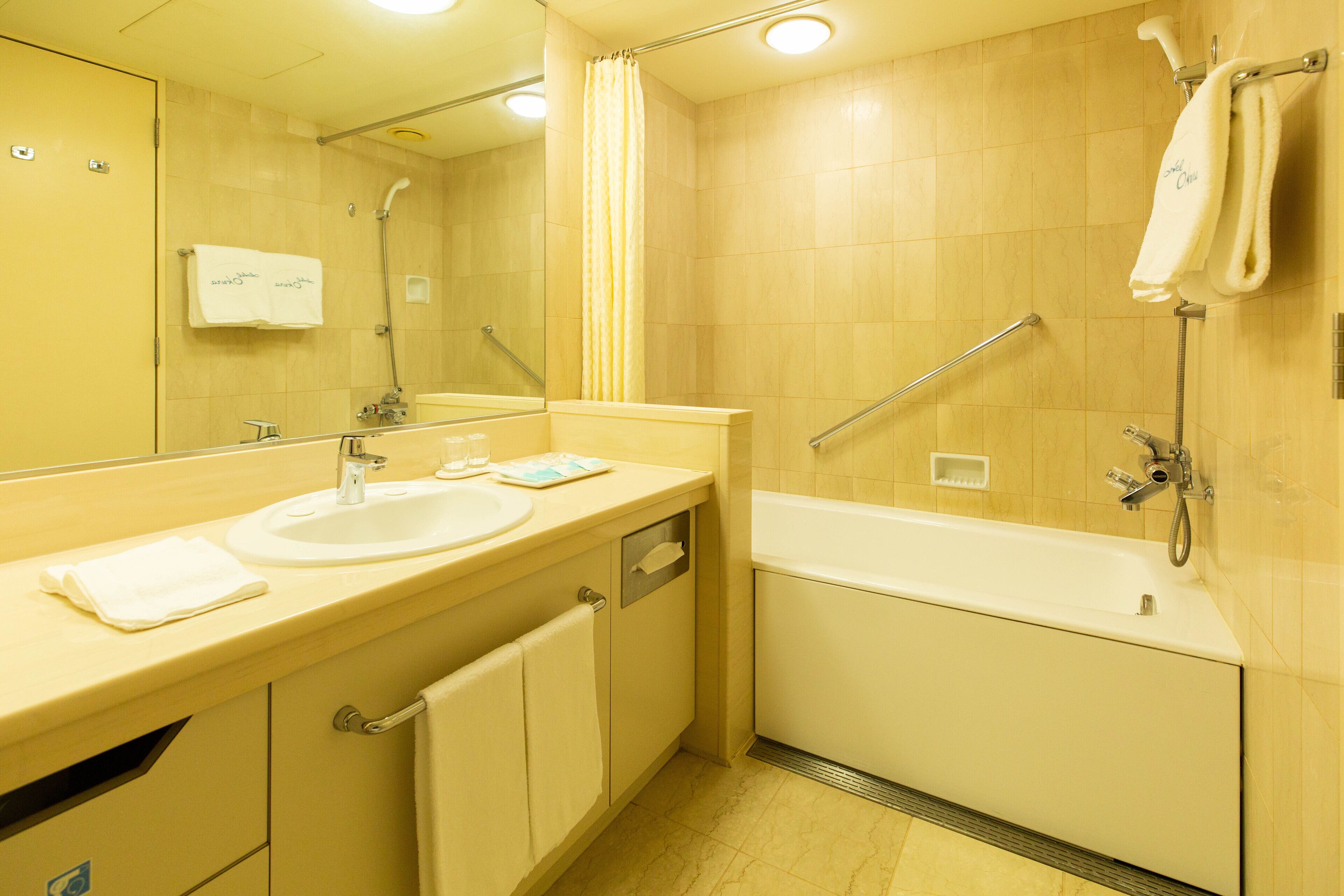 A bathroom with a sink, mirror, shower, and bathtub.