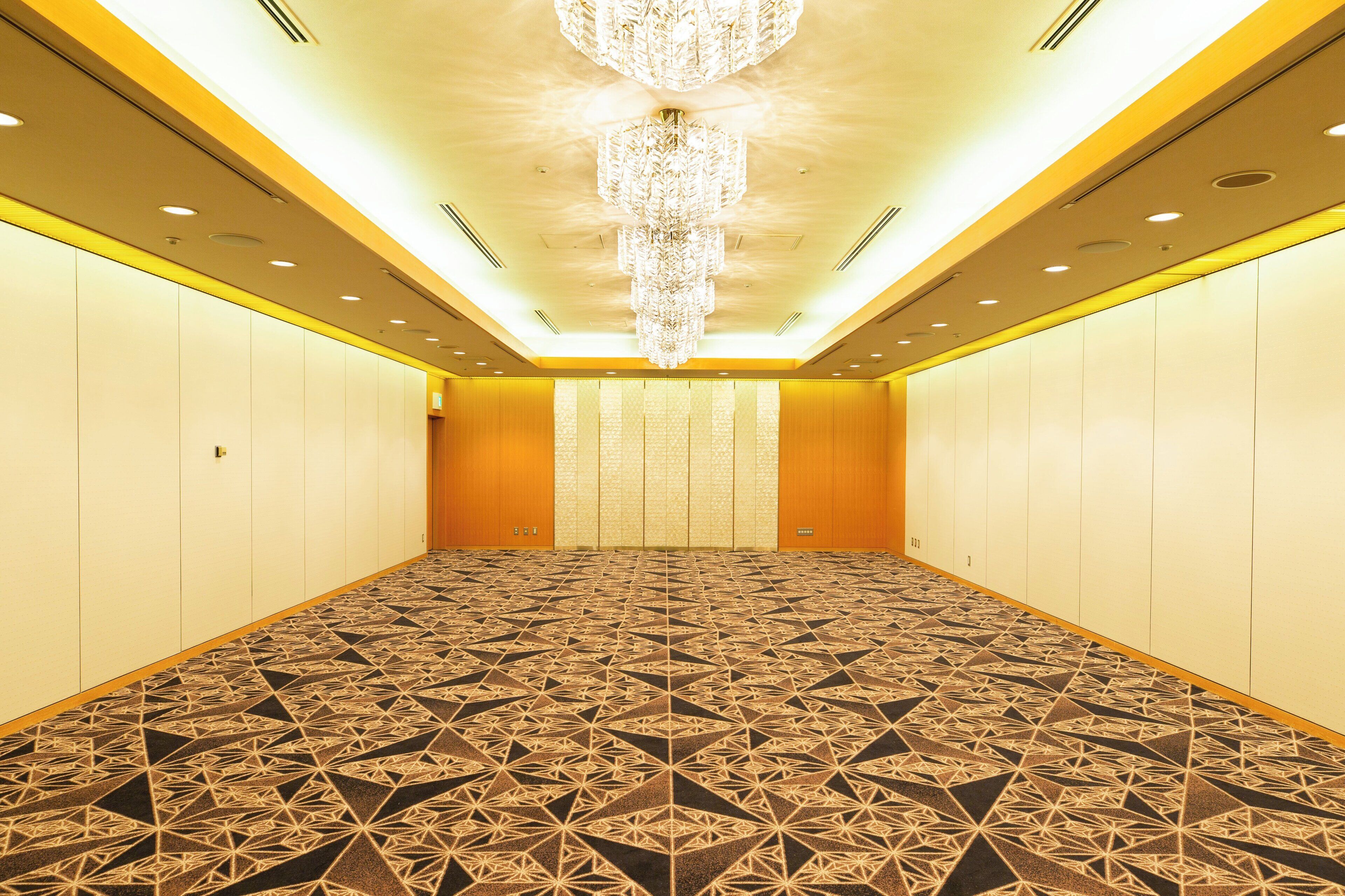 A hotel room with a patterned carpet, a chandelier, and a row of lockers along the walls.