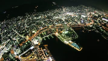 An aerial view of a cityscape at night with illuminated buildings, roads, and a river.