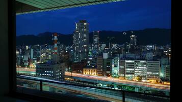 A nighttime cityscape with illuminated buildings and a highway.