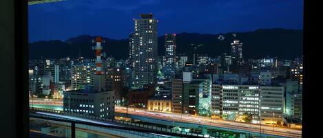 Un paisaje urbano nocturno con edificios iluminados y una autopista.
