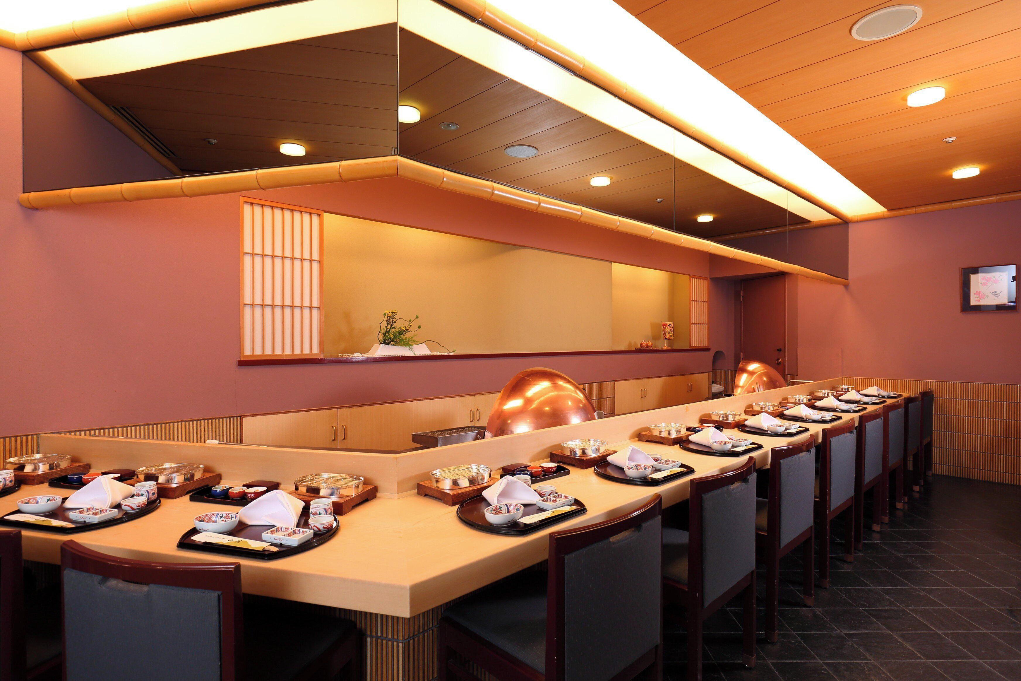 A long dining table set with multiple dishes and a mirror above it.