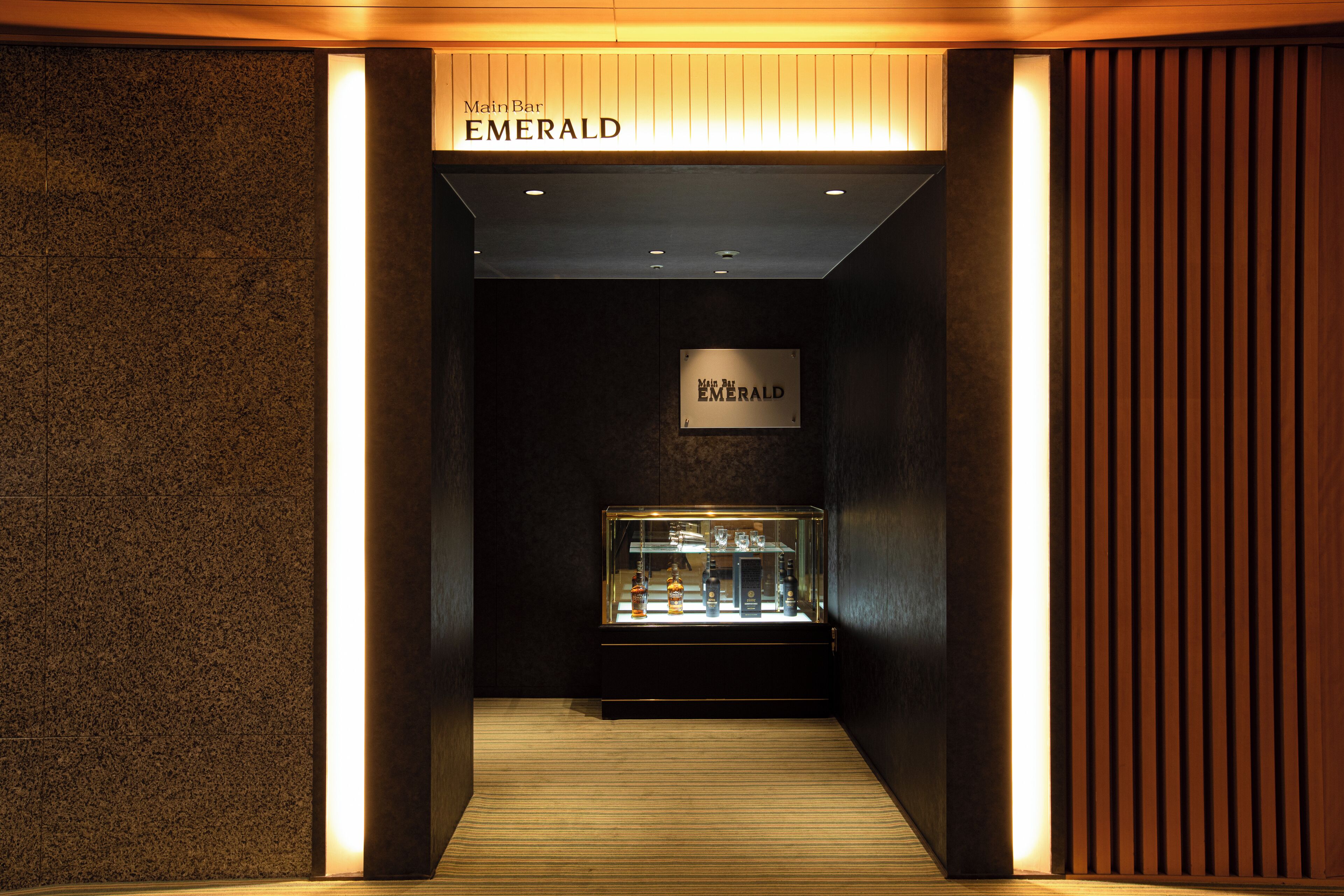 A hallway with a sign reading "Emerald" and a display case with bottles.