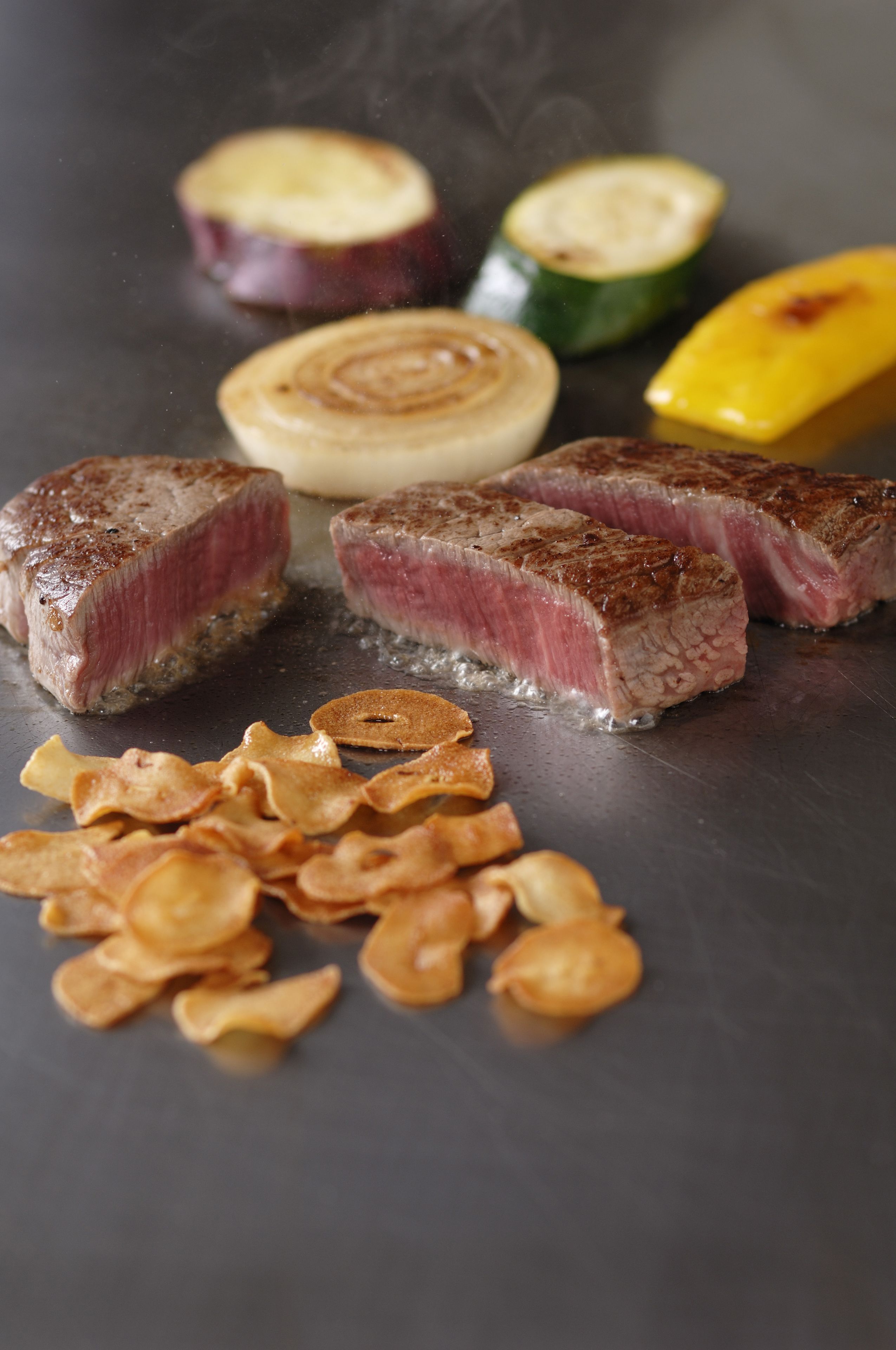 Un filete con verduras y papas fritas sobre una parrilla.