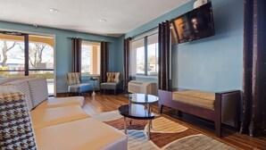 A modern living room with a sofa, armchairs, a small table, and a TV mounted on the wall. - Best Western Eunice (Eunice)