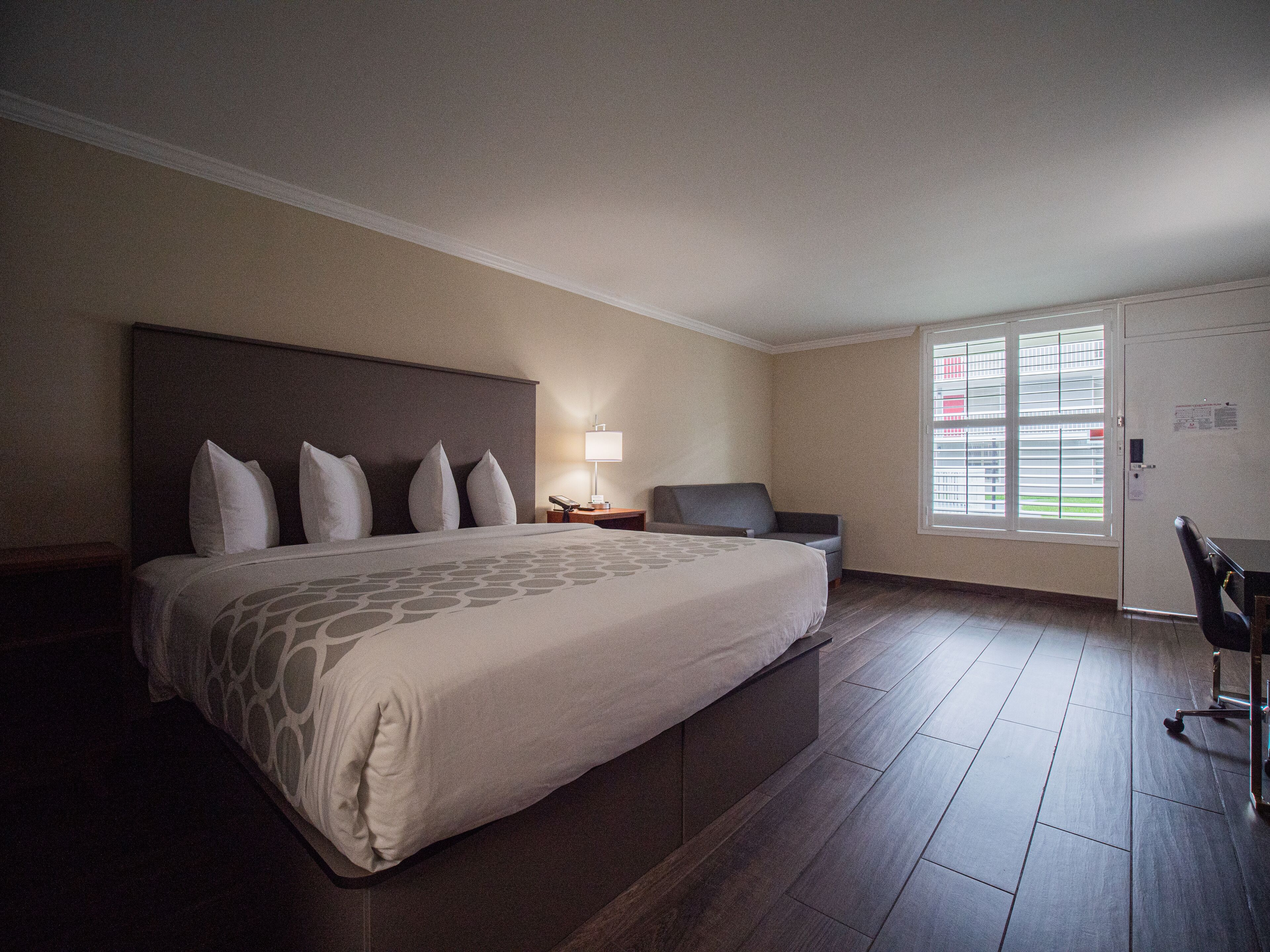 A hotel room with a large bed, a desk, and a chair.