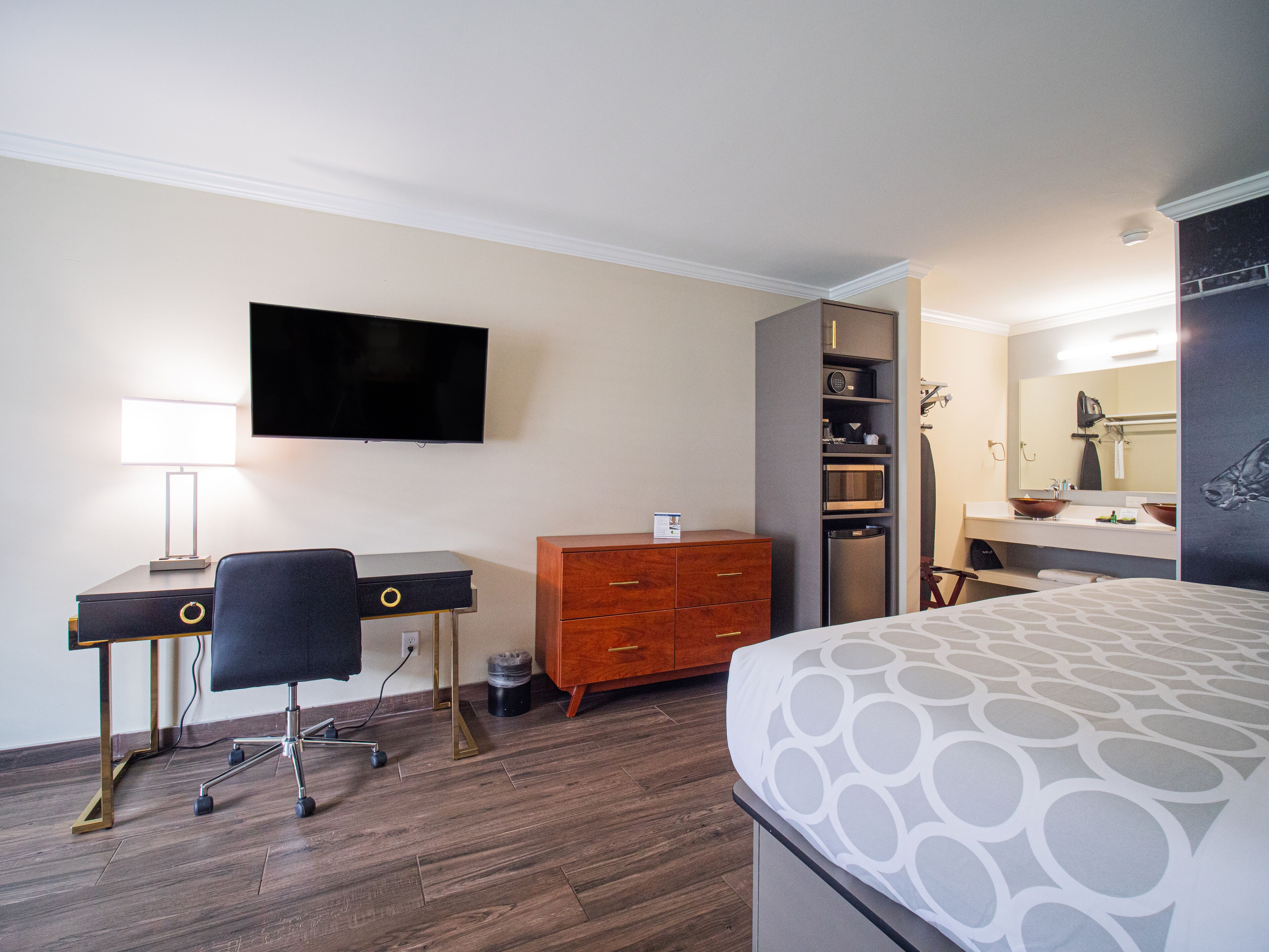 Une chambre d’hôtel équipée d’un lit, d’un bureau, d’une chaise, d’une télévision, d’une armoire et d’une salle de bain avec un lavabo et un miroir.