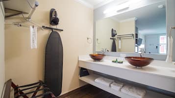 Ein Badezimmer mit einem großen Spiegel, zwei Waschbecken mit Kupferbecken, einem Handtuchhalter und einem Holzstuhl.
