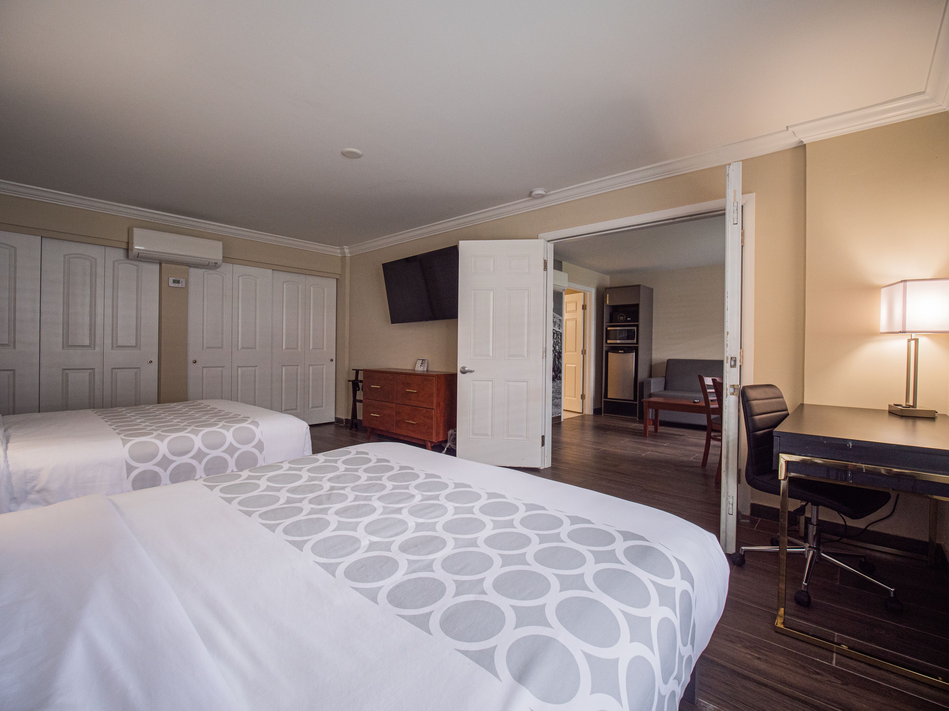 A hotel room with two beds, a desk, a chair, a TV, and a wardrobe.