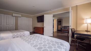 A hotel room with two beds, a desk, a chair, a TV, and a wardrobe.