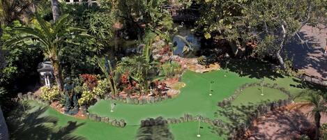 Un parcours de mini-golf comportant plusieurs trous, entouré d’une végétation luxuriante et agrémenté d’un petit étang.