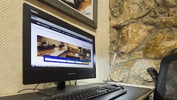 A computer monitor displaying a hotel website with a room layout, a keyboard, and a mouse on a desk.