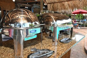A buffet setup with stainless steel chafing dishes labeled 'Sausage' and 'Chicken'.