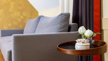 Una sala de estar moderna con un sofá gris, una mesita de madera con un florero blanco con flores, y un jarrón con flores blancas.